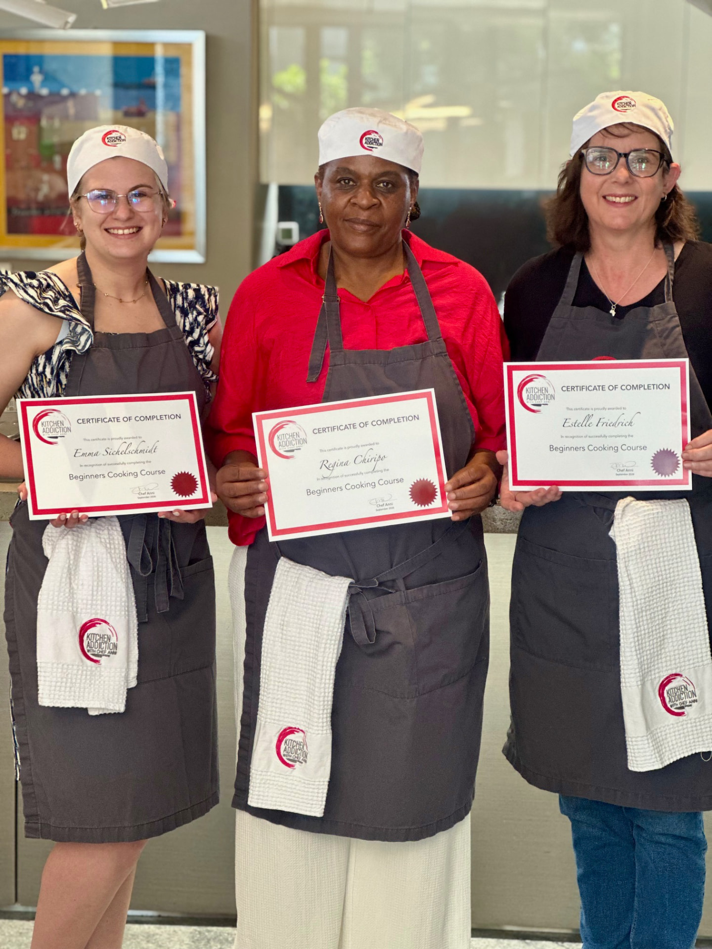 Three graduates proudly holding their Beginners Cooking Course completion certificates